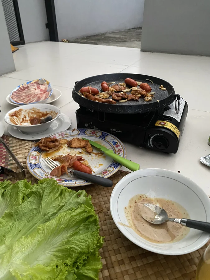 Pan BBQ sewaan dipakai memanggang daging dan sosis saat piknik